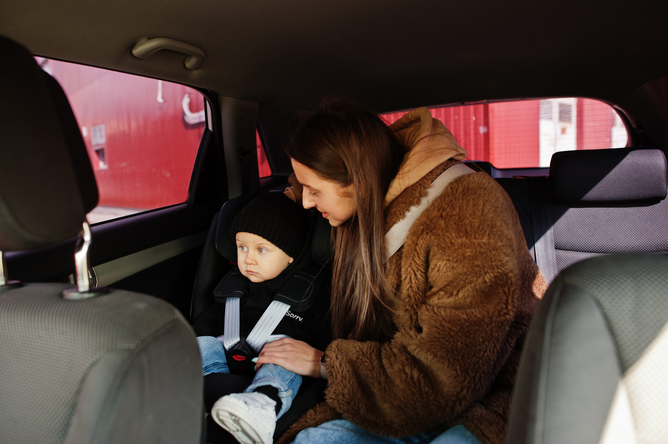 Young mother and child in car. Baby seat on chair. Safety driving concept.